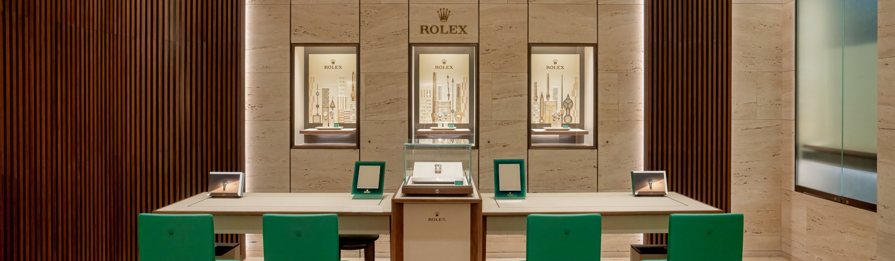 Innenansicht einer Rolex Niederlassung mit einem Tisch und 4 grünen Stühlen